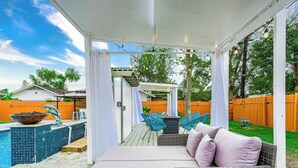 An outdoor patio with a covered seating area, a pool, and a fenced backyard. - Empress Outdoor Luxury Villa (Houston)