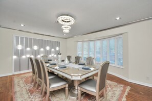 Uma sala de jantar com uma mesa grande, cadeiras e um candelabro.