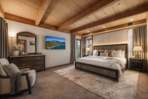 Ein Schlafzimmer mit einem großen Bett, einem Schminktisch, einem Sessel, einem Gemälde und Blick ins Freie.