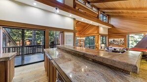 A spacious kitchen with a granite countertop, wooden beams, and large windows. - Lx16 Luxe Martis Landing Sauna, Gameroom and Hot Tub (Truckee)