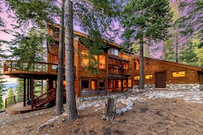 A multi-level wooden cabin with a stone foundation, large windows, and a deck. - Lx16 Luxe Martis Landing Sauna, Gameroom and Hot Tub (Truckee)