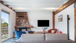 Uma sala de estar com lareira de pedra, televisão de tela plana e um sofá.