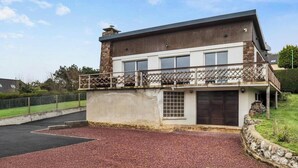 Uma casa de dois andares com varanda, garagem e entrada para carros.