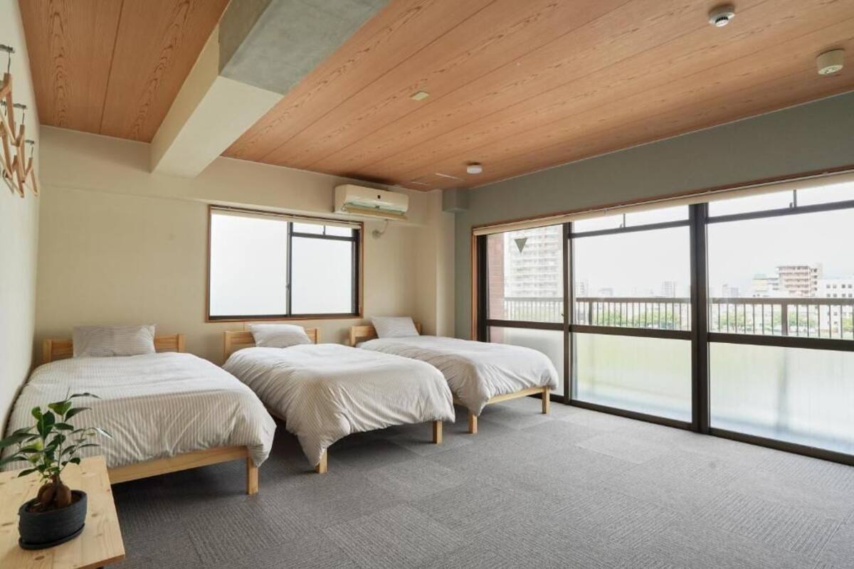 A hotel room with three beds, large windows, and a ceiling with wooden beams.