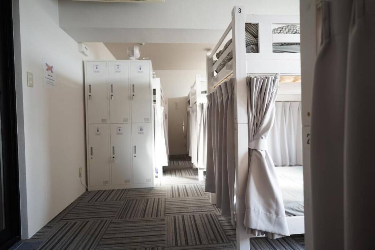 A hotel corridor with bunk beds, a carpeted floor, and lockers.