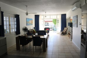 A dining area with a table and chairs, a ceiling fan, and a view through a glass door to the outside. - Luxury and complete apartment near the sea (Willemstad)