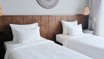 Une chambre d’hôtel avec deux lits, un élément décoratif mural, un luminaire en fibres tressées et une table de chevet avec une télécommande.