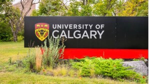 A sign for the University of Calgary with a logo, surrounded by greenery. - Rocky Ridge Retreat — Your Gateway to the Rockies (Calgary)