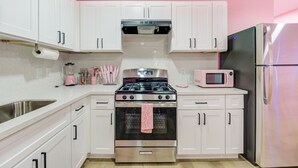 Una cucina con mobili bianchi, un piano cottura in acciaio inossidabile, un forno a microonde e un frigorifero.