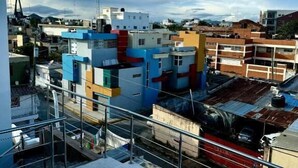 A residential area with colorful buildings, a swimming pool, and a view of the cityscape. - Room-hotel Maria Bonita Higüey H301 (Higuey)
