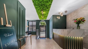A reception area with a green wall, a reception desk, a green ceiling, and a view of the outside. - Corner Suite The Valour in De Waterkant (Cape Town)