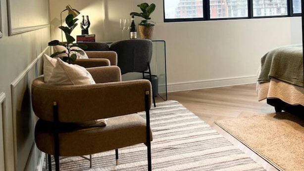 A modern living room with a large window, a flat-screen TV, a sofa, and a bed. - Corner Suite The Valour in De Waterkant (Cape Town)