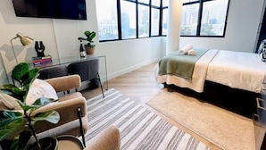 A modern hotel room with a bed, a desk, a chair, a TV, and large windows. - Corner Suite The Valour in De Waterkant (Cape Town)