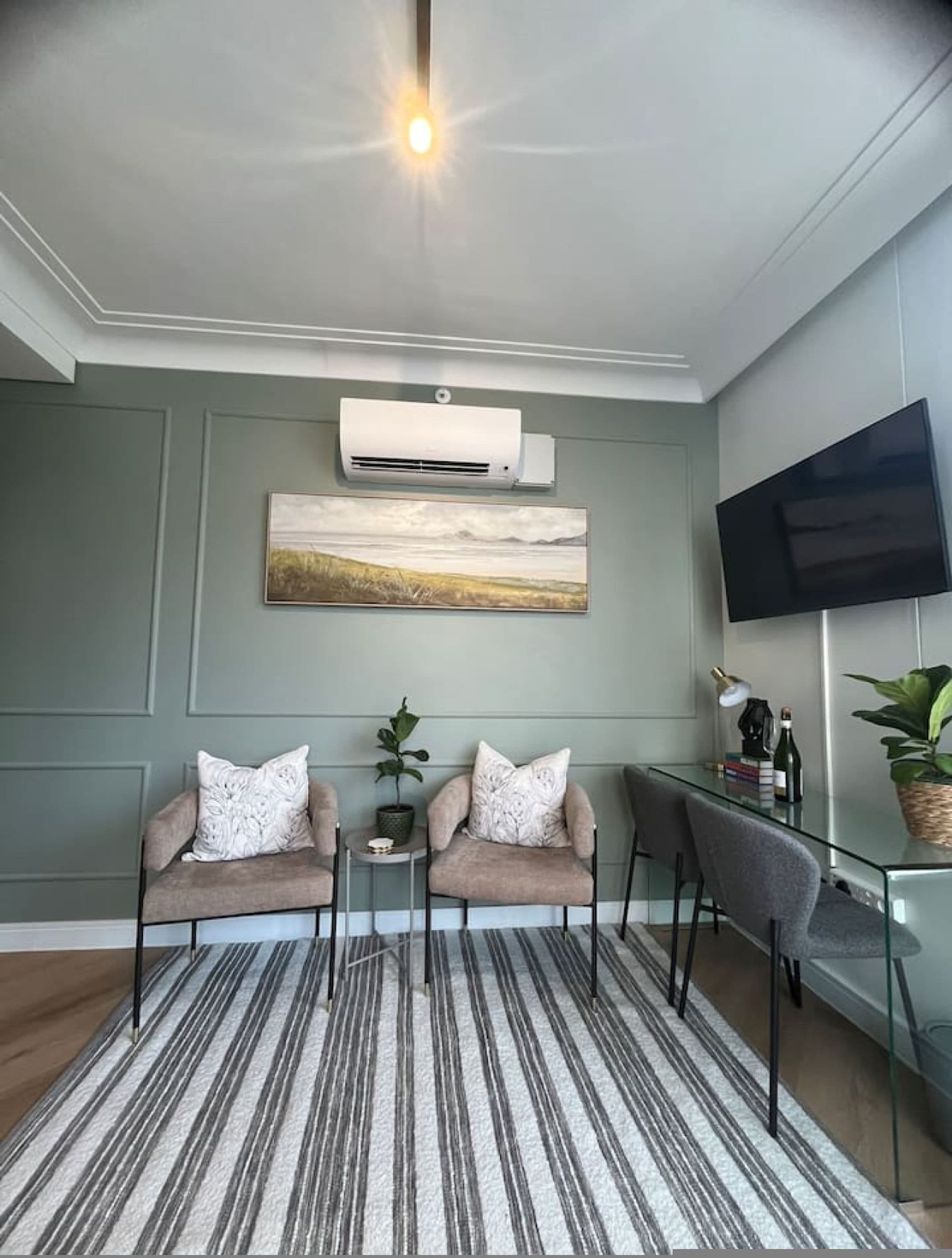 A modern living room with two sofas, a coffee table, a flat-screen TV, and an air conditioning unit.