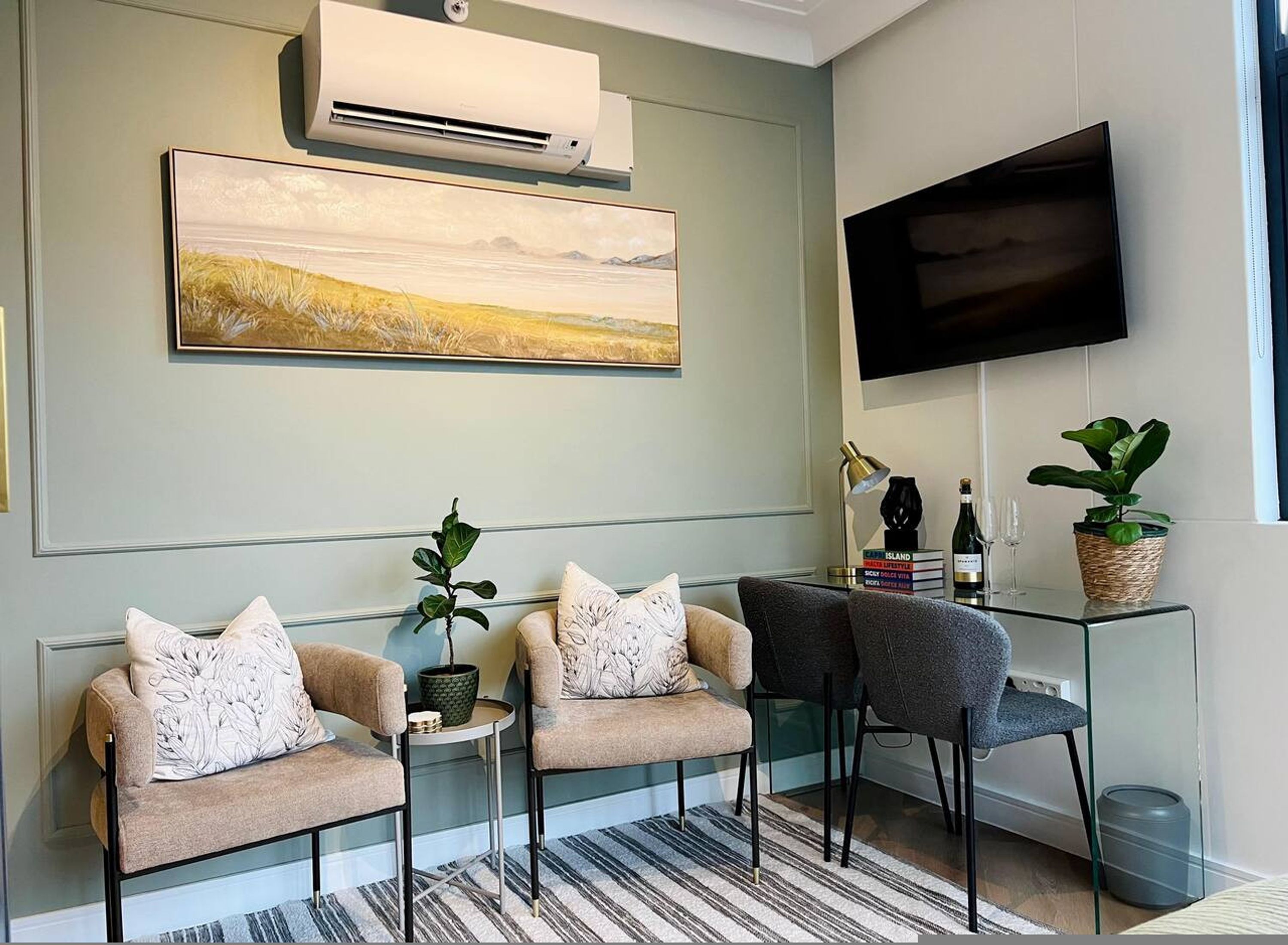 A modern living room with a sofa set, a small table, a TV, and a painting on the wall.