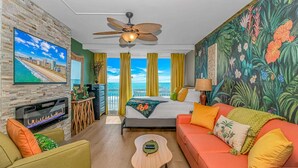 A hotel room with a bed, a sofa, a TV, a ceiling fan, and a balcony with a view. - Yachtsman S502 Studio (Myrtle Beach)