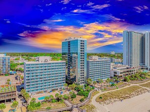 Ein Hochhaus-Hotel mit mehreren Etagen, einem Schwimmbecken und einem Strandbereich.