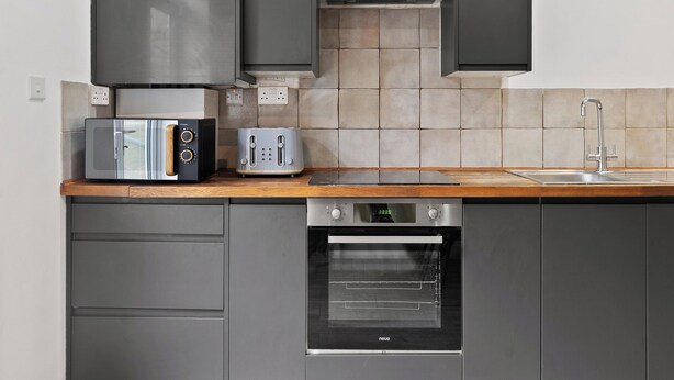 A kitchen with a microwave, toaster, oven, and a wooden countertop. - Cosy 2 Bed-5 Guests-Garden-Parking&WiFi (London)