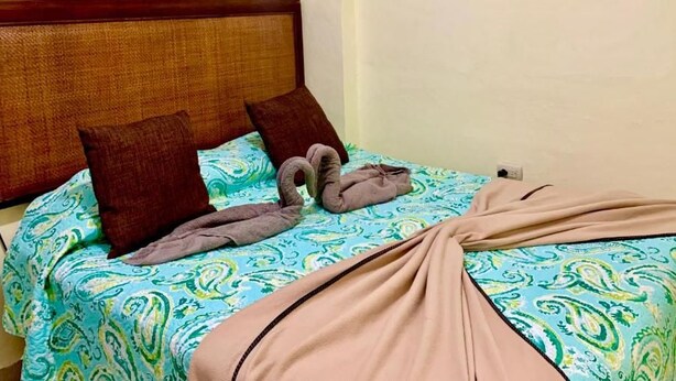 A bed with a patterned bedspread, two pillows, and a blanket. - Room-hotel Maria Bonita Higüey H3 (Higuey)