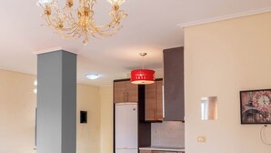 Une cuisine moderne équipée d’un réfrigérateur, d’une cuisinière et d’un luminaire rouge suspendu au plafond.