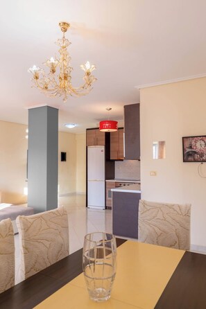 A modern kitchen with a refrigerator, stove, and a red hanging light fixture. - Albania Dream Saranda Apartments (Saranda)