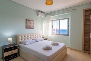A bedroom with a bed, bedside table, and a window with a view. - Albania Dream Saranda Apartments (Saranda)