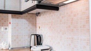 A modern kitchen with a black induction cooktop, stainless steel kettle, and a built-in range hood. - Albania Dream Saranda Apartments (Saranda)