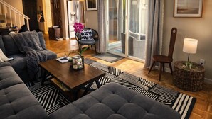 Ein geräumiges Wohnzimmer mit einem großen grauen Sofa, einem Holztisch und einer Treppe, die in eine obere Etage führt.