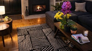 Ein Wohnzimmer mit Kamin, Fernseher, einer Couch und einem Couchtisch mit Blumen.