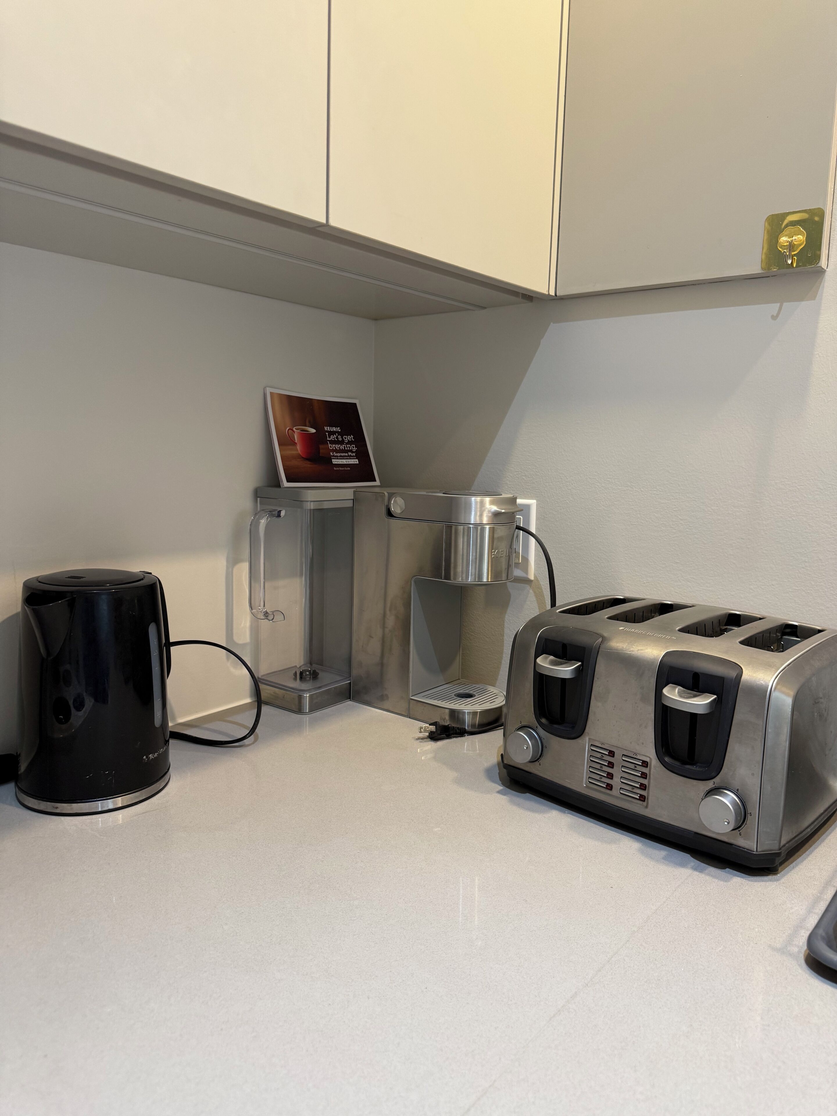 A kitchenette with a coffee maker, a toaster, and a coffee machine.