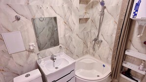 Une salle de bain comprenant des toilettes, un lavabo, une douche et une baignoire, le tout avec des murs et des sols en marbre.