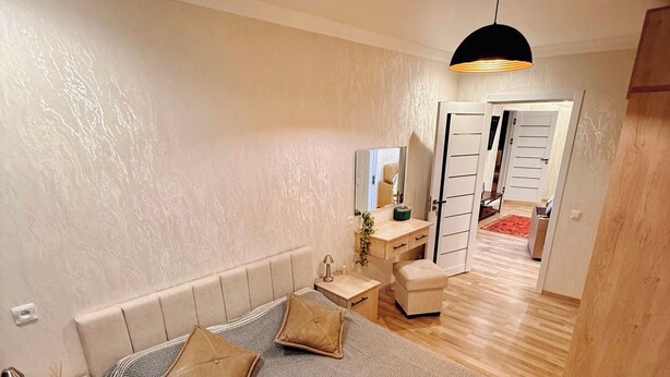 Une chambre à coucher comprenant un lit, des tables de chevet, une commode, un miroir et un luminaire suspendu.