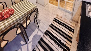 Un coin repas avec une nappe à carreaux, un four à micro-ondes et un tapis à motifs.