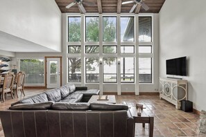 A spacious living room with a large sectional sofa, a flat-screen TV, and a dining area with chairs and a table. - 5BR Lake Conroe Waterfront | 3 Kings + Private Dock | Swim + Fish | Games + Fire Pit | Sleeps 12 (Montgomery)