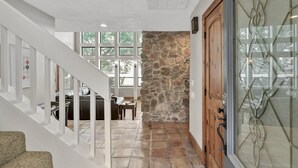 A staircase leading to a living area with a stone wall, a wooden door, and a glass door with a decorative metal frame. - 5BR Lake Conroe Waterfront | 3 Kings + Private Dock | Swim + Fish | Games + Fire Pit | Sleeps 12 (Montgomery)