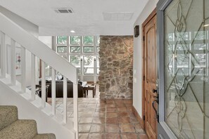 A staircase leading to a living area with a stone wall, a wooden door, and a glass door with a decorative metal frame. - 5BR Lake Conroe Waterfront | 3 Kings + Private Dock | Swim + Fish | Games + Fire Pit | Sleeps 12 (Montgomery)