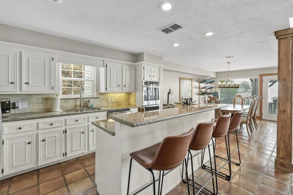 A spacious kitchen with white cabinets, a granite countertop, and a large island with bar stools. - 5BR Lake Conroe Waterfront | 3 Kings + Private Dock | Swim + Fish | Games + Fire Pit | Sleeps 12 (Montgomery)