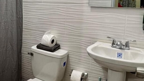 A bathroom with a toilet, a sink, and a shower curtain. - Room-hotel Maria Bonita Higüey H304 (Higuey)