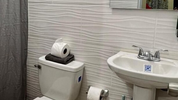 A bathroom with a toilet, a sink, and a shower curtain. - Room-hotel Maria Bonita Higüey H304 (Higuey)