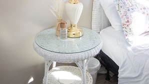 Een kamer met een wit bed, een witte lamp op een glazen tafel, een ster decoratie aan de muur en een ingelijst certificaat.