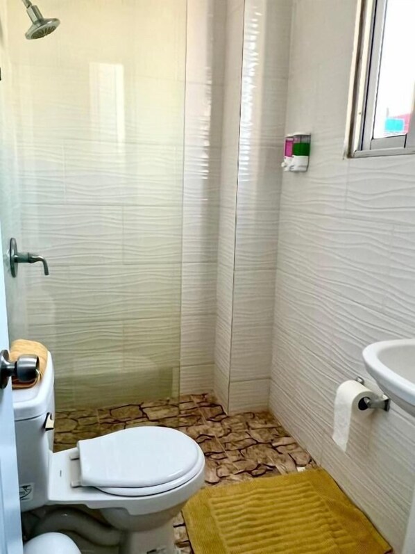 A small bathroom with a toilet, a shower, a sink, and a patterned floor. - Room-hotel Maria Bonita Higüey H302 (Higuey)