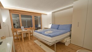 A compact room with a bed, a desk, a chair, and a wardrobe. - Studio Rollin, Haus Rollin (Zermatt)