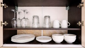 A kitchen cabinet with glassware, plates, and bowls. - Airport Studio-Quick City Access w/ Free Parking (Surčin)