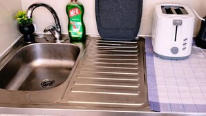 A kitchen with a sink, a dish soap bottle, a toaster, and a black cutting board. - Airport Studio-Quick City Access w/ Free Parking (Surčin)