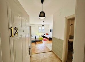 Käytävän päästä on pääsy makuuhuoneeseen, jossa on sänky, tuoli ja riippuvalaisin.
