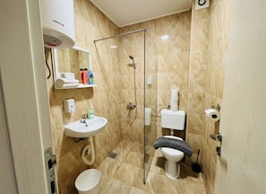 Een badkamer met douche, toilet, wastafel en een handdoekhouder.