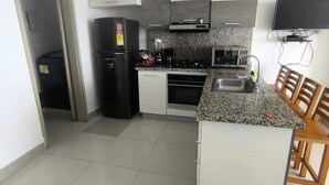A modern kitchen with a refrigerator, stove, microwave, and granite countertop. - The little house on the beach (Cartagena de Indias)