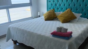 A bed with a tufted headboard, a patterned bedspread, and two pillows. - The little house on the beach (Cartagena de Indias)