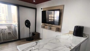 A modern kitchen with a marble countertop, a built-in TV, and a ceiling fan. - The little house on the beach (Cartagena de Indias)