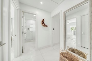 A hallway with white walls, a wooden crescent moon decoration, and a wicker basket. - Mermaid Retreat – Coastal Paradise Just Steps from Sombrero Beach (Marathon)